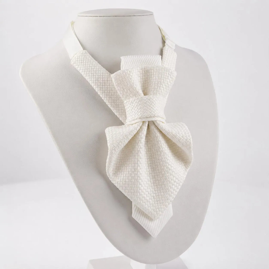 An off-white textured bow tie displayed on a white mannequin bust against a clean white background Luxury handmade white textile neck accessories for women, showcasing elegant designer statement chokers with textured fabric, satin bows, and delicate pearl pendants. Displayed on soft ivory fabric, these premium artisan accessories are handcrafted for brides, weddings, bridal showers, formal occasions, and timeless fashion. Featuring matching bridal styles and minimalist designs, each piece reflects couture-i