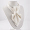 An off-white textured bow tie displayed on a white mannequin bust against a clean white background Luxury handmade white textile neck accessories for women, showcasing elegant designer statement chokers with textured fabric, satin bows, and delicate pearl pendants. Displayed on soft ivory fabric, these premium artisan accessories are handcrafted for brides, weddings, bridal showers, formal occasions, and timeless fashion. Featuring matching bridal styles and minimalist designs, each piece reflects couture-i