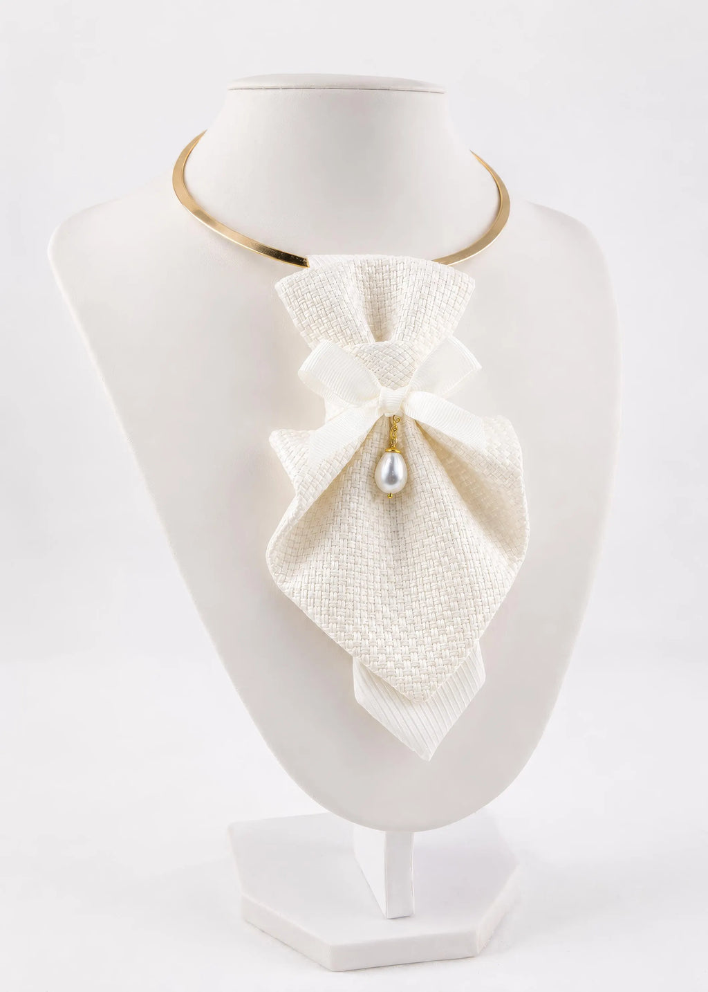 A white textured fabric bow collar necklace with a small pearl drop and gold metal accents, displayed on a white mannequin bust Luxury handmade white textile neck accessories for women displayed on soft ivory fabric. Elegant designer statement chokers featuring textured fabric, satin bows, and a pearl pendant, handcrafted for brides, weddings, bridal showers, formal occasions, and timeless fashion. Premium artisan accessories showcasing matching bridal and minimalist designs with couture-inspired craftsmans