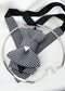 Black and white houndstooth Hopper Tie with a black neck strap and a silver-tone rigid necklace laid on white fabric.