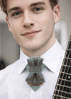 Man wearing a unique bow tie design with a blurred background  green bow tie for men, hopper tie birch design, modern bow tie close up, handmade necktie from lithuania, artistic bow tie texture detail, green yellow bow tie, luxury pre tied bow tie, unique wedding bow tie, contemporary bow tie design, nature inspired bow tie, men formal neck accessory, bow tie for musicians, summer wedding bow tie, green bow tie texture, designer bow tie close shot
