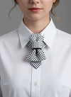 Person wearing a white shirt with a black and white polka dot bow tie against a gray background