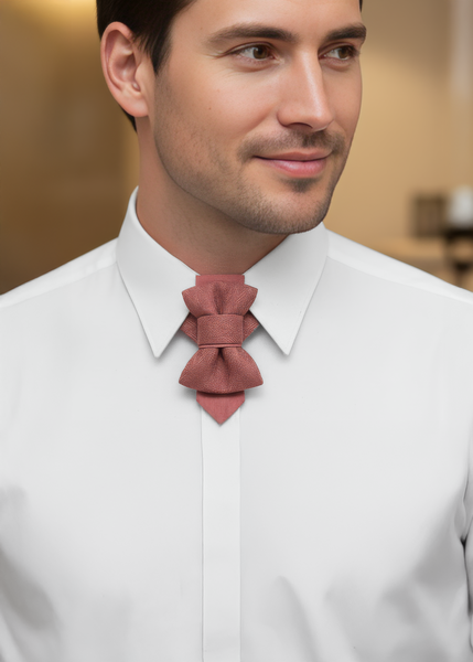 Man in a suit sitting at a cafe table with a cup of coffee, looking out the window wearing original design pink wedding bow tie