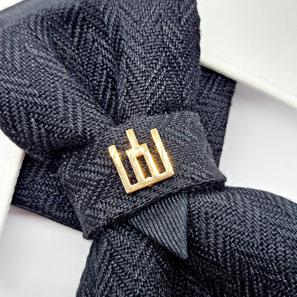 Black textured headband with a gold logo on a white background Handmade luxury dark navy blue wool bow tie with leather neck strap and unique gold-tone monogrammed clip. Pre-tied cravat for groom, weddings, formal events, and special occasions. Perfect sophisticated men's accessory.