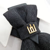 Black textured bow tie with a gold clasp on a white background