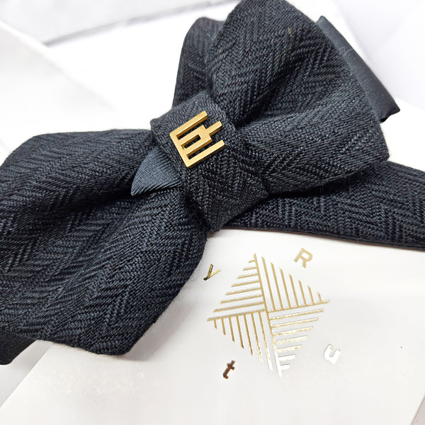 Dark gray herringbone patterned headband with a gold bow on a white background Handmade luxury dark navy blue wool bow tie with leather neck strap and unique gold-tone monogrammed clip. Pre-tied cravat for groom, weddings, formal events, and special occasions. Perfect sophisticated men's accessory.