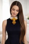 Woman wearing a black dress with a large gold bow accessory handmade luxury neck accessory, women statement tie, vertical bow tie for women, gold satin necktie, elegant women tie, unique bow tie alternative, luxury handmade tie, artistic neckwear for women, modern formal accessory, gold statement necklace tie, designer women necktie, wedding guest accessory women, avant garde fashion tie, silk bow tie alternative, bold women fashion accessory, golden necktie women, formal outfit statement piece stylish offi