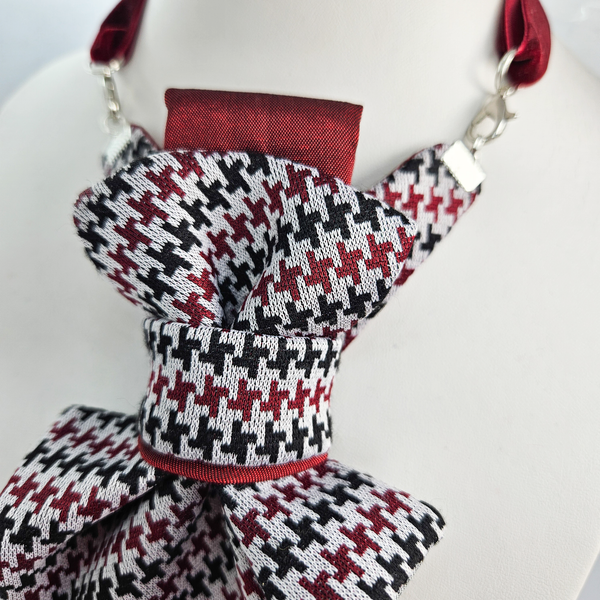 Houndstooth patterned scarf with red accents on a mannequin against a white background premium handmade knitted houndstooth tie in burgundy, luxury italian silk wool blend necktie with red pied-de-poule pattern, unique red and black patterned tie for wedding or business attire, close-up of high-quality wool knit scarf style tie with abstract design, elegant burgundy and black dogtooth patt