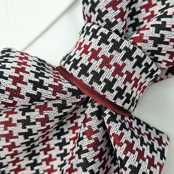 Close-up of a knitted bow with a houndstooth pattern on a white background premium handmade knitted houndstooth tie in burgundy, luxury italian silk wool blend necktie with red pied-de-poule pattern, unique red and black patterned tie for wedding or business attire, close-up of high-quality wool knit scarf style tie with abstract design, elegant burgundy and black dogtooth patt