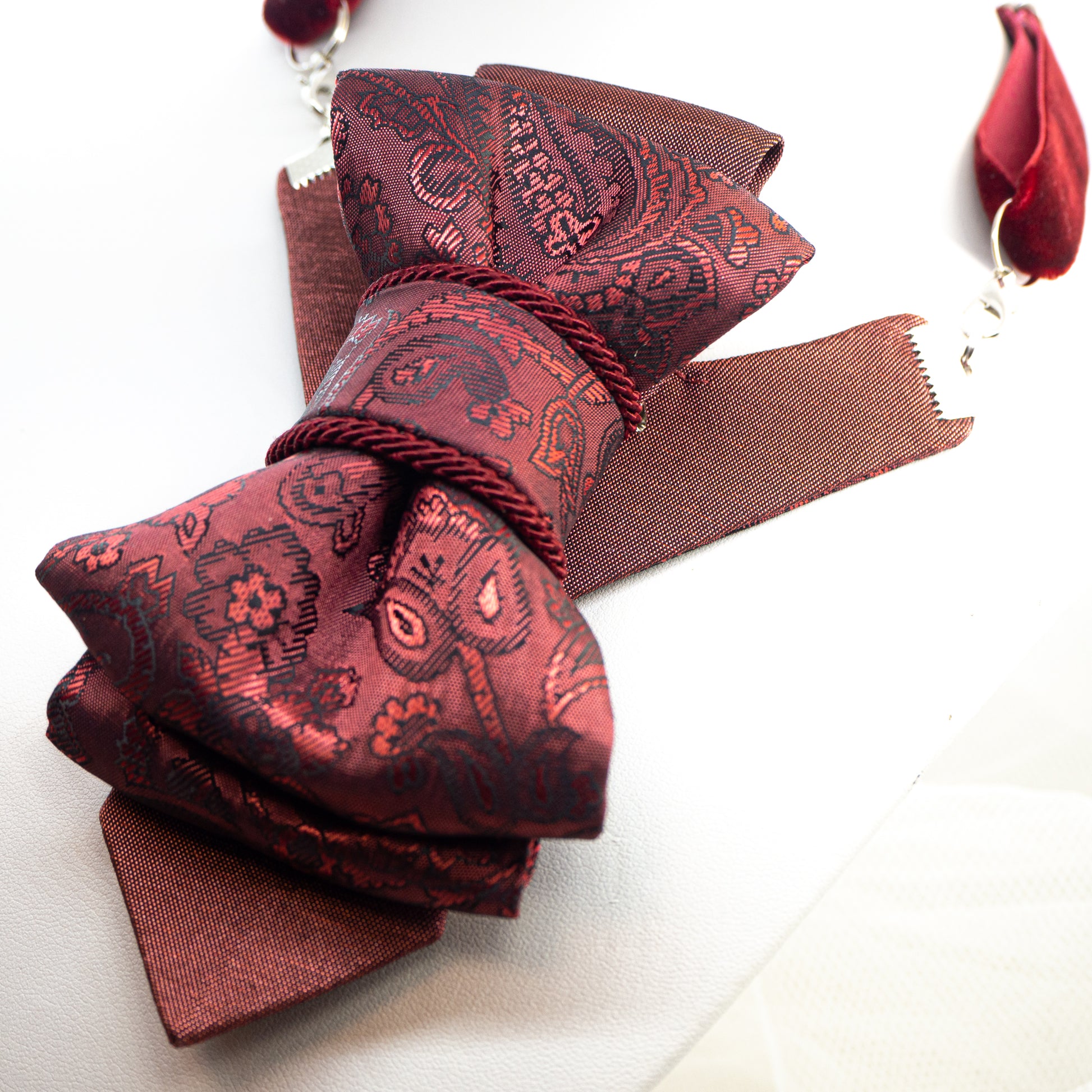 red bow tie, vertical bow tie, luxury womens tie, handmade tie, statement neckwear, unique bow tie, elegant tie for women, double-sided tie, brooch tie, pendant tie, rose wine tie, wedding accessory, business fashion, fashion necktie, Rūta Piekurienė design, artistic tie, unisex tie, special occasion tie, decorative tie, floral pattern tie, modern bow tie, Lithuanian handmade, pre-tied bow tie, gift for her