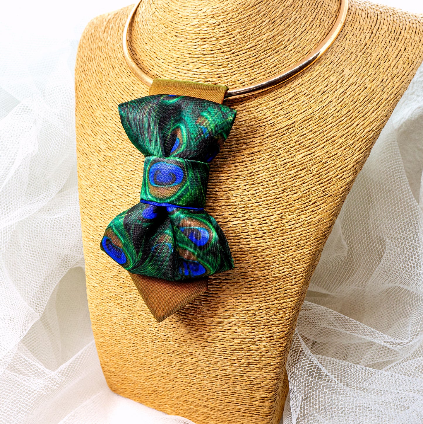 BOW TIE HOPPER TIE PEACOCK Woman wearing a stylish necklace with peacock feathers and a gray blazer peacock feather necklace, statement bow tie necklace, handmade silk accessory, green blue peacock pattern jewelry, artistic neckpiece, elegant women accessory, unique designer necklace, luxury handmade jewelry, modern bow necklace, bold statement piece, peacock motif fashion, gift for her unique jewelry, sustainable handmade accessory, artisan neckwear, teal green fashion accessory